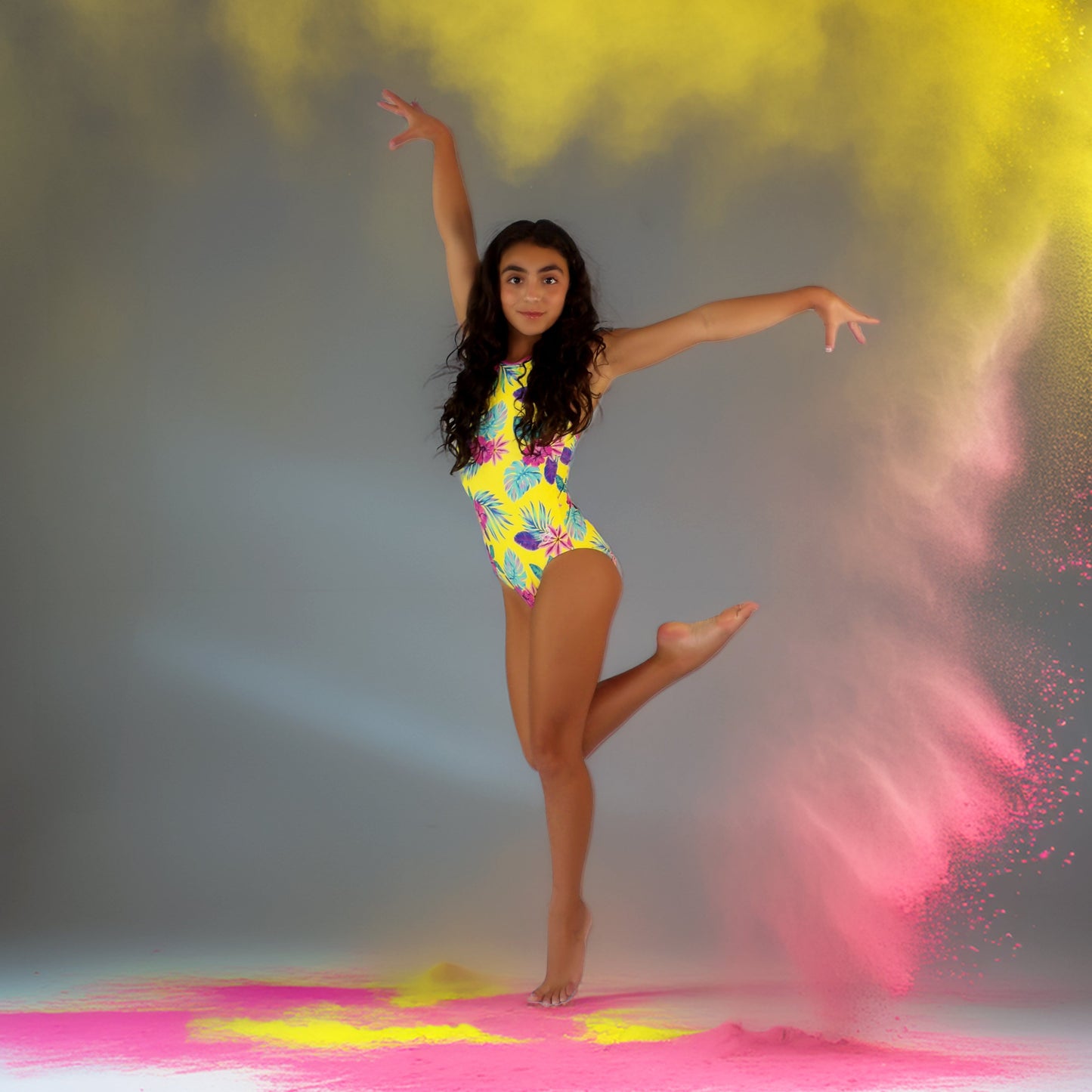 Dancer gymnast in a colorful outfit with yellow and pink powder effects on a gray background